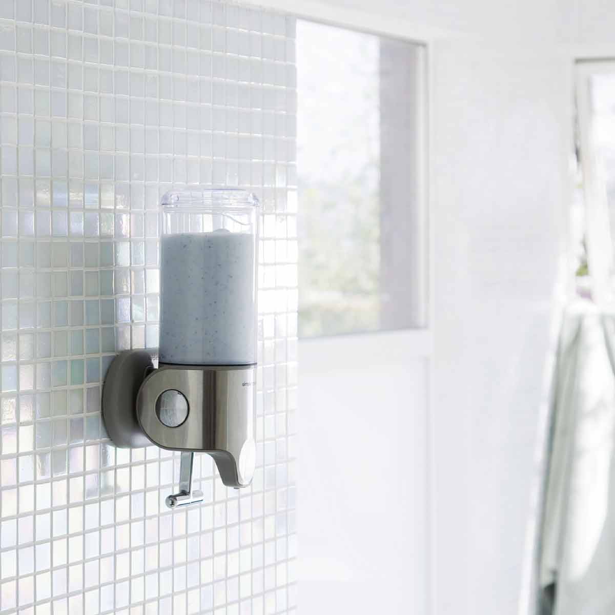Angled view of Simplehuman Single Wall Mount Pump in Brushed Stainless Steel, space-saving shower dispenser