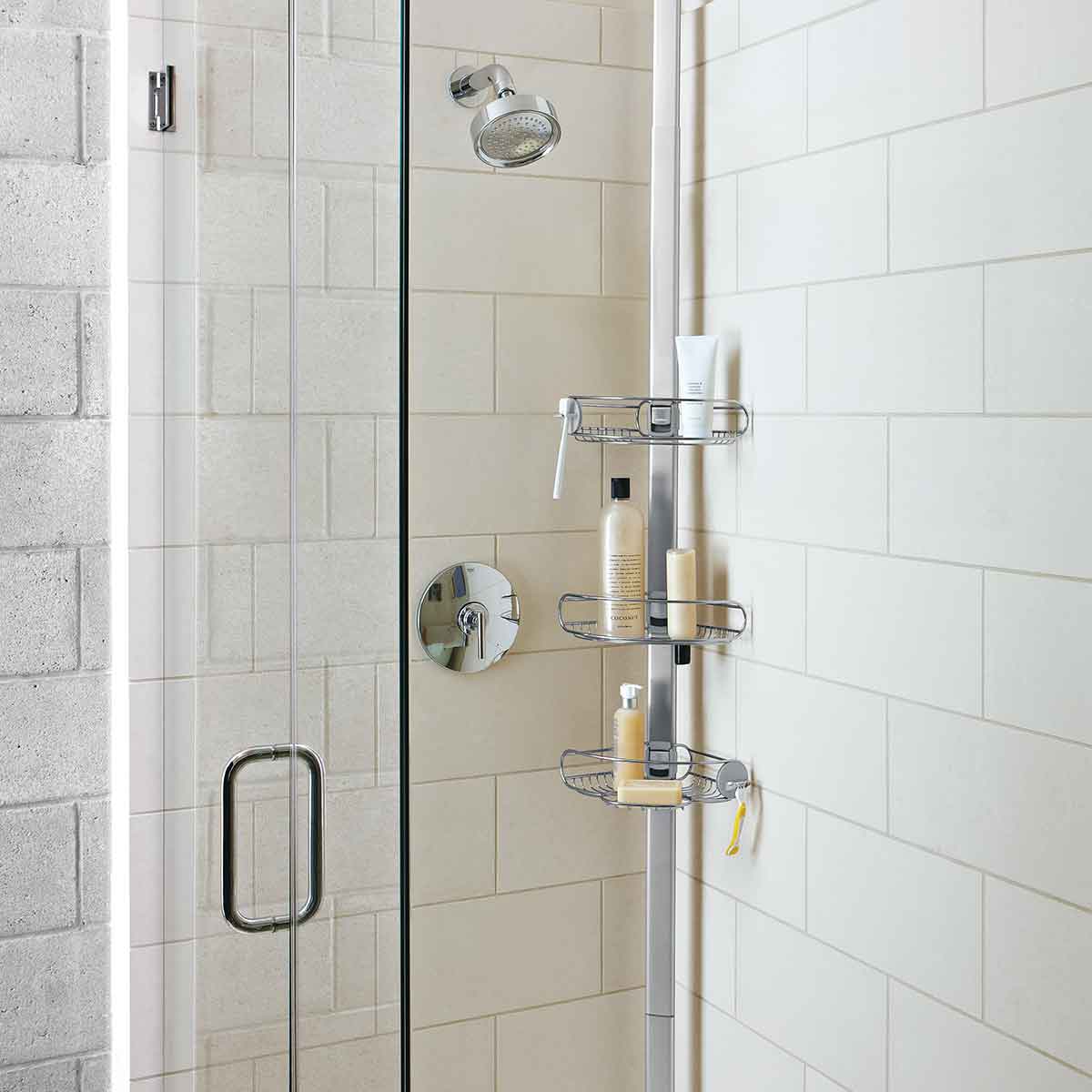 Angled view of Simplehuman Tension Shower Caddy, White/Polished Stainless Steel, adjustable shelves for maximizing vertical shower storage.