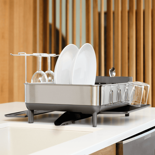 Simplehuman Brushed Stainless Steel Steel Frame Dishrack angled view on a countertop, drying plates and wine glasses with integrated drainage.
