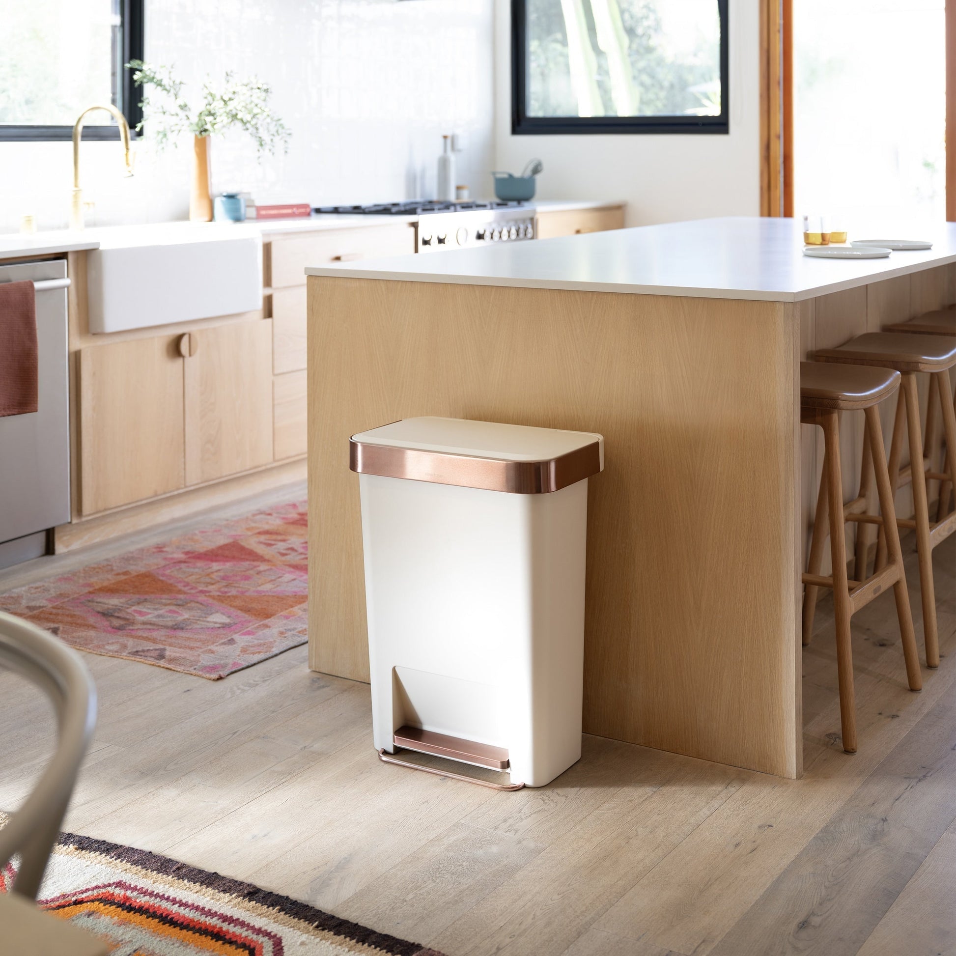 Lifestyle view of Simplehuman 45L Hybrid Step Can, Cream/Rose Gold, shown in a modern kitchen setting.