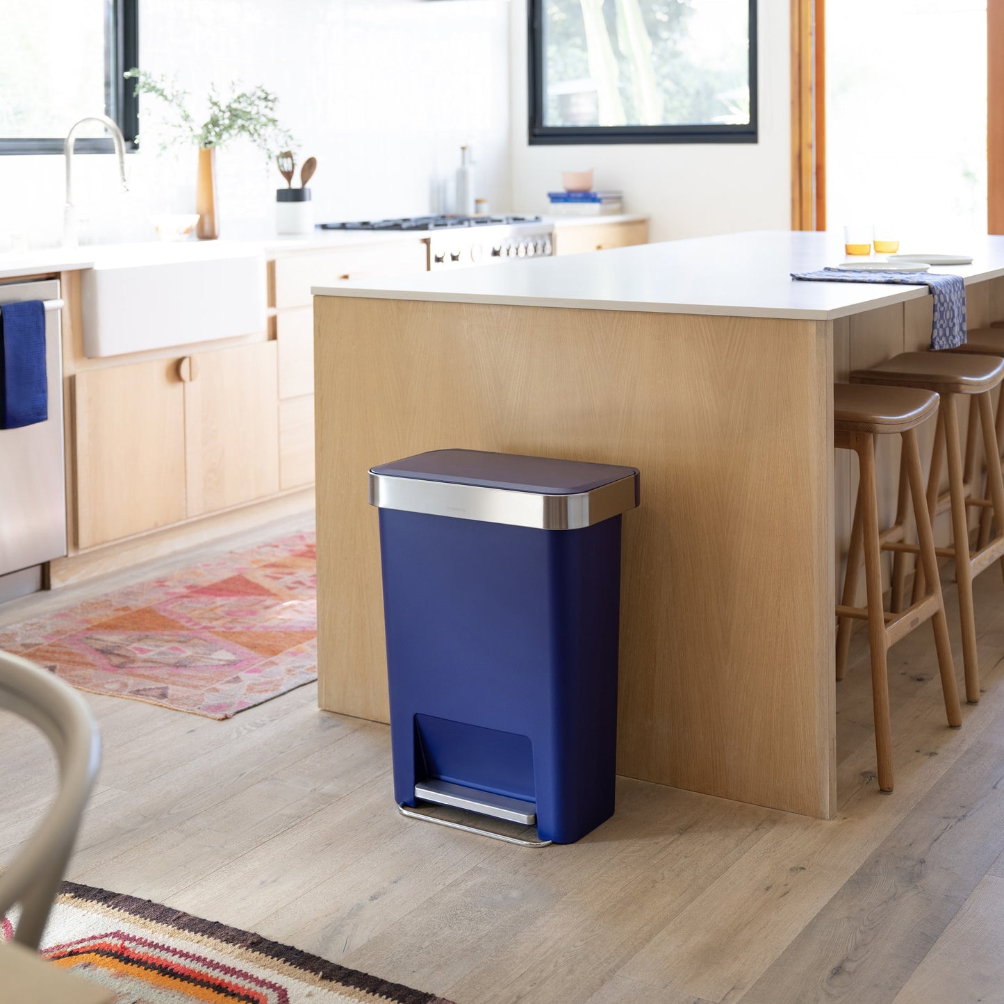 Simplehuman 45L Hybrid Step Can, Ultra Violet, hands-free pedal, resting against a light wood kitchen island.