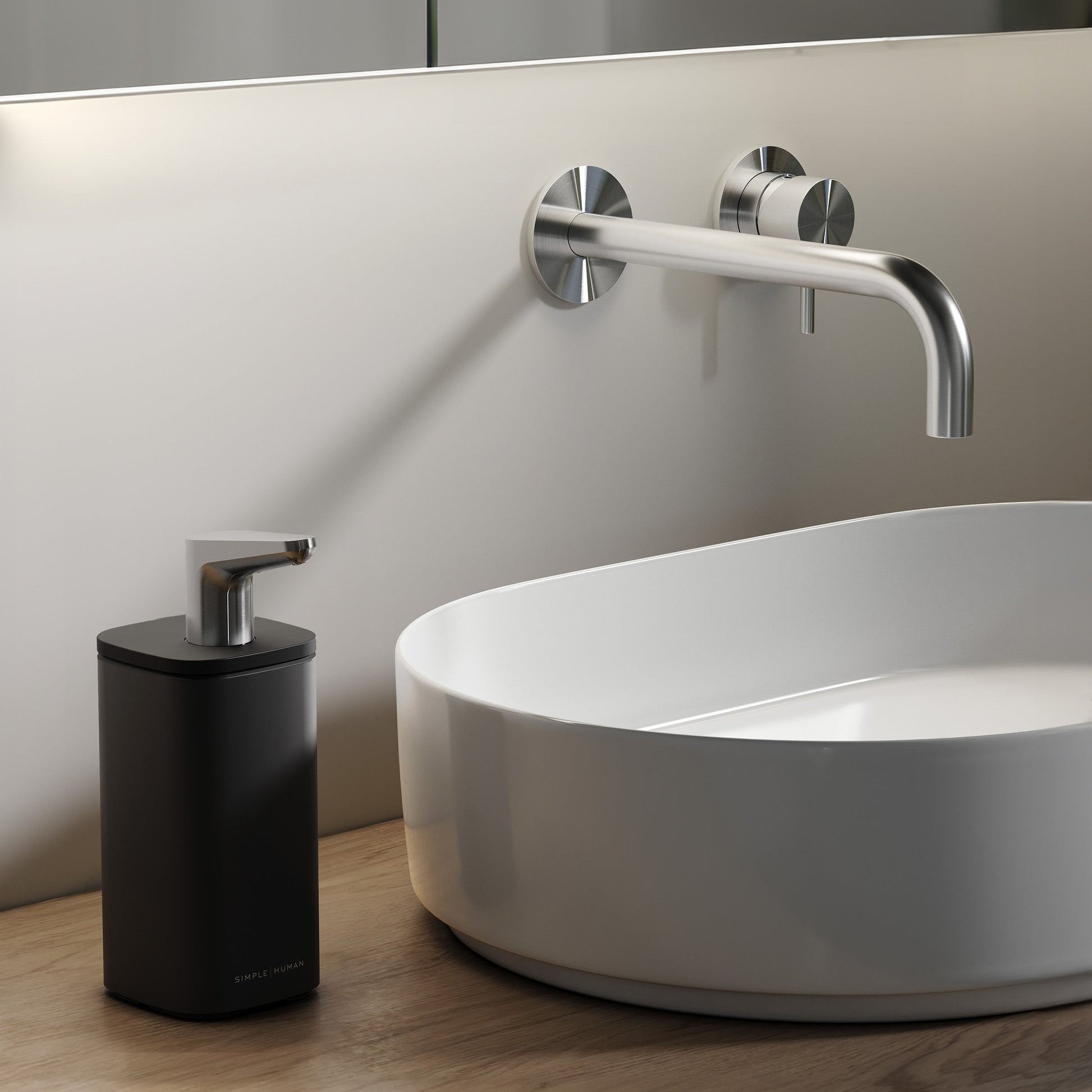 Simplehuman Matte Black 10 oz. Pulse Pump on a wooden bathroom vanity beside a white vessel sink.