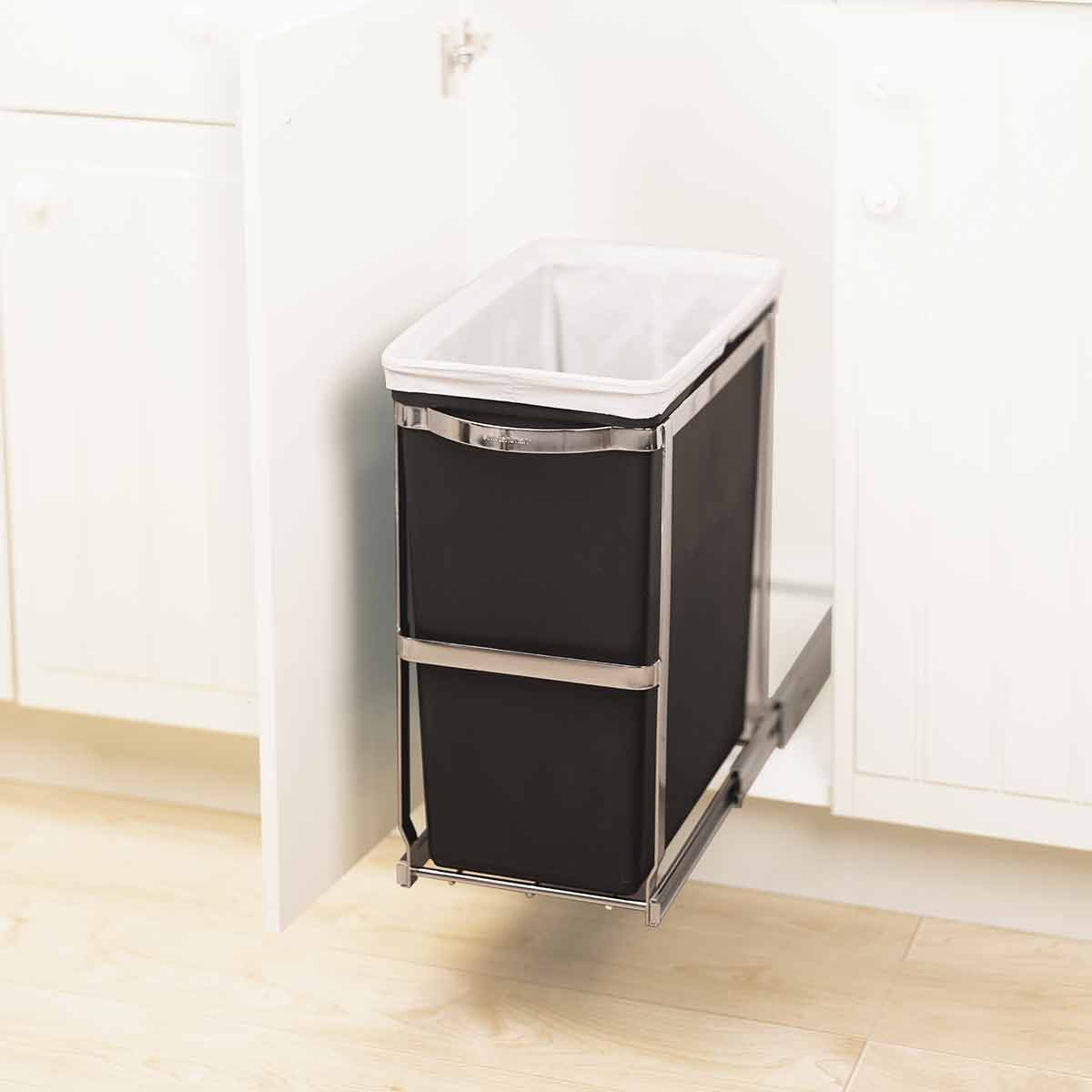 Detail view of Simplehuman 30L Pull-Out Can, Polished Stainless Steel frame holding black liner, fully extended under cabinet.
