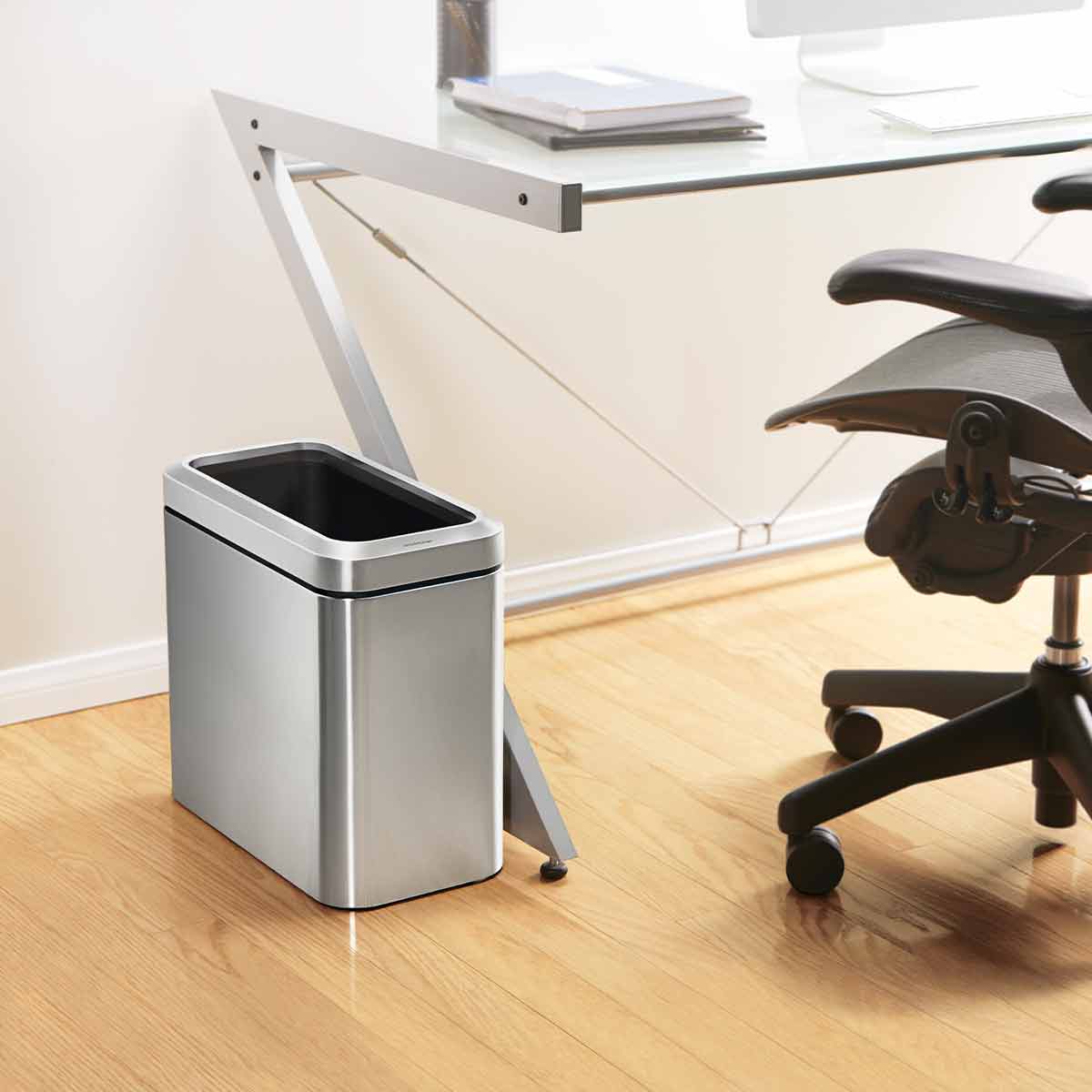 Lifestyle view of Simplehuman 25L Slim Open Can Brushed Stainless Steel under desk, space-saving.