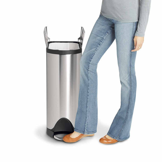 Lifestyle view of Simplehuman 30L Butterfly Step Can, Brushed Stainless Steel, demonstrating hands-free pedal and butterfly lid usage.