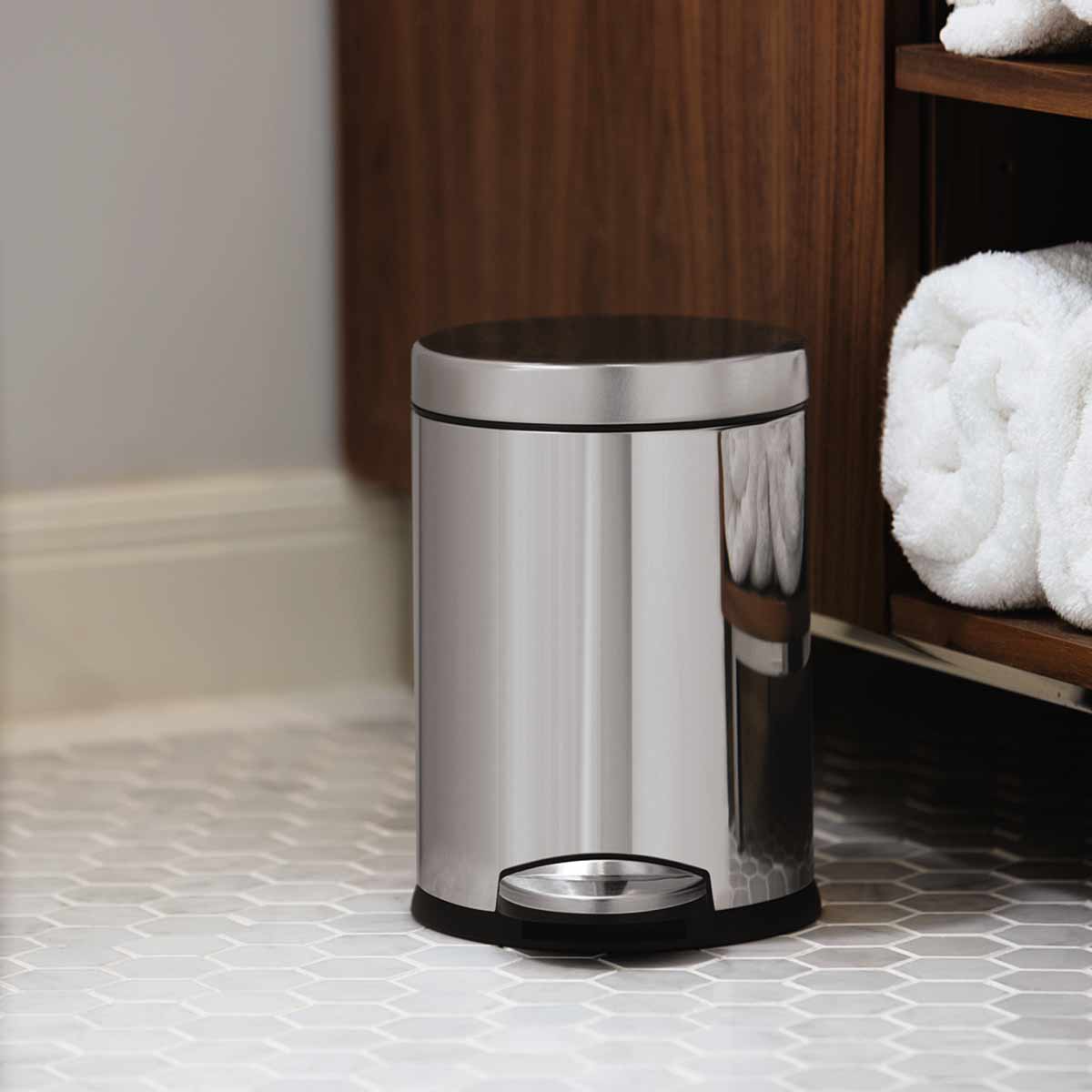 Lifestyle view of Simplehuman 4.5L Round Step Can, Polished Stainless Steel, compact for bathroom use, hands-free pedal.