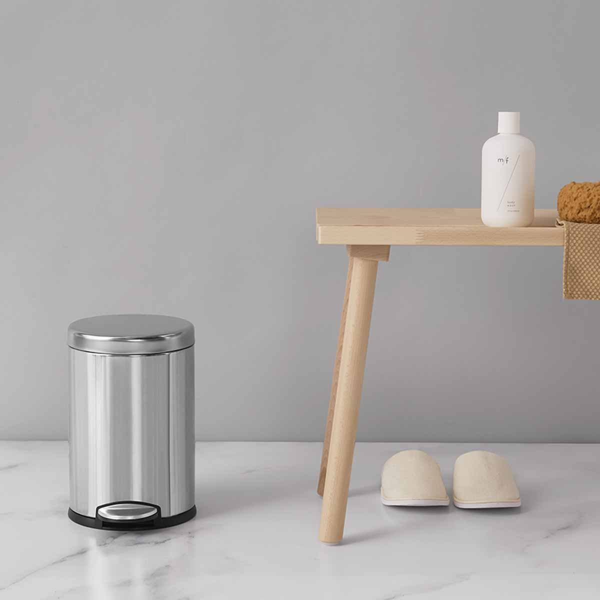 Lifestyle view of Simplehuman 4.5L Round Step Can, Brushed Stainless Steel, small size for bathroom use, hands-free pedal.