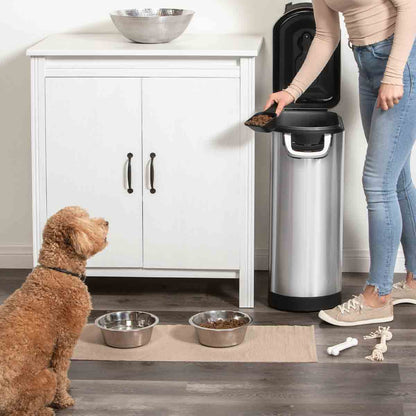 Lifestyle view of Simplehuman X-Large Pet Food Can, Brushed Stainless Steel, open for easy scooping while feeding a dog.