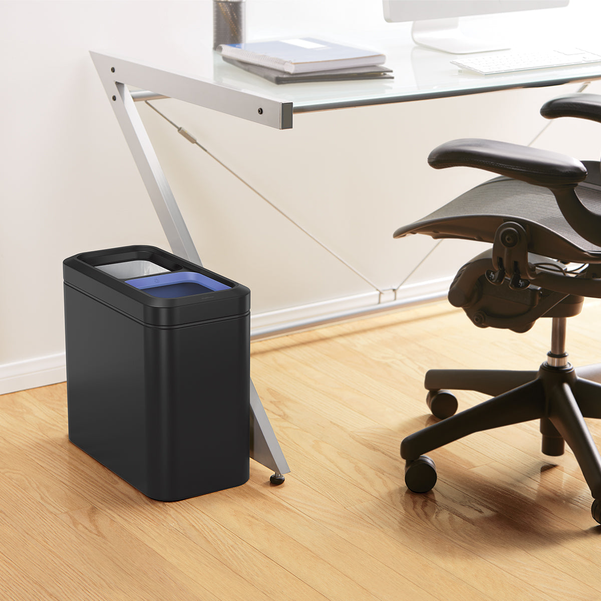 Simplehuman Matte Black 20L Dual Slim Open Can beside an office chair, hands-free recycling solution.
