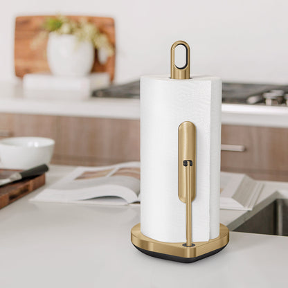 Angled view of Simplehuman Brass Tension Arm Paper Towel Holder on counter, adjustable tension for one-handed tear.