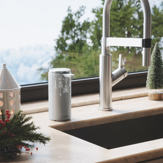 Lifestyle view of Simplehuman Silver Metallic 2024 Holiday Sleeve (9 oz.) in a winter kitchen setting, snowflake design.