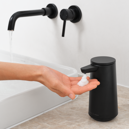Simplehuman Matte Black Sensor Pump Foam dispensing foam soap into a hand at a modern sink, touch-free.